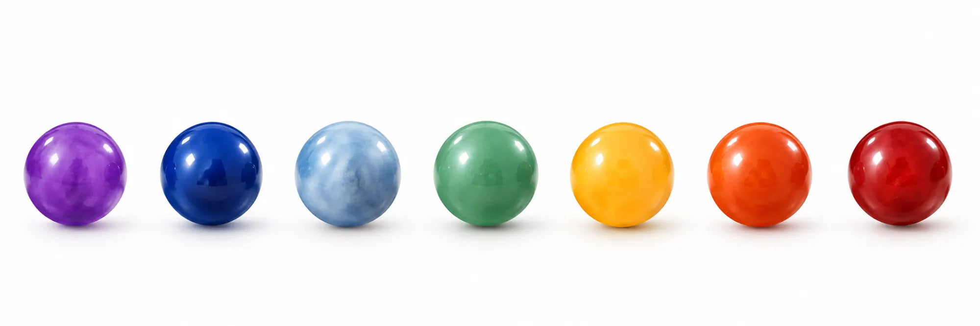 Seven polished coloured beads in violet, indigo, blue, green, yellow, orange and red