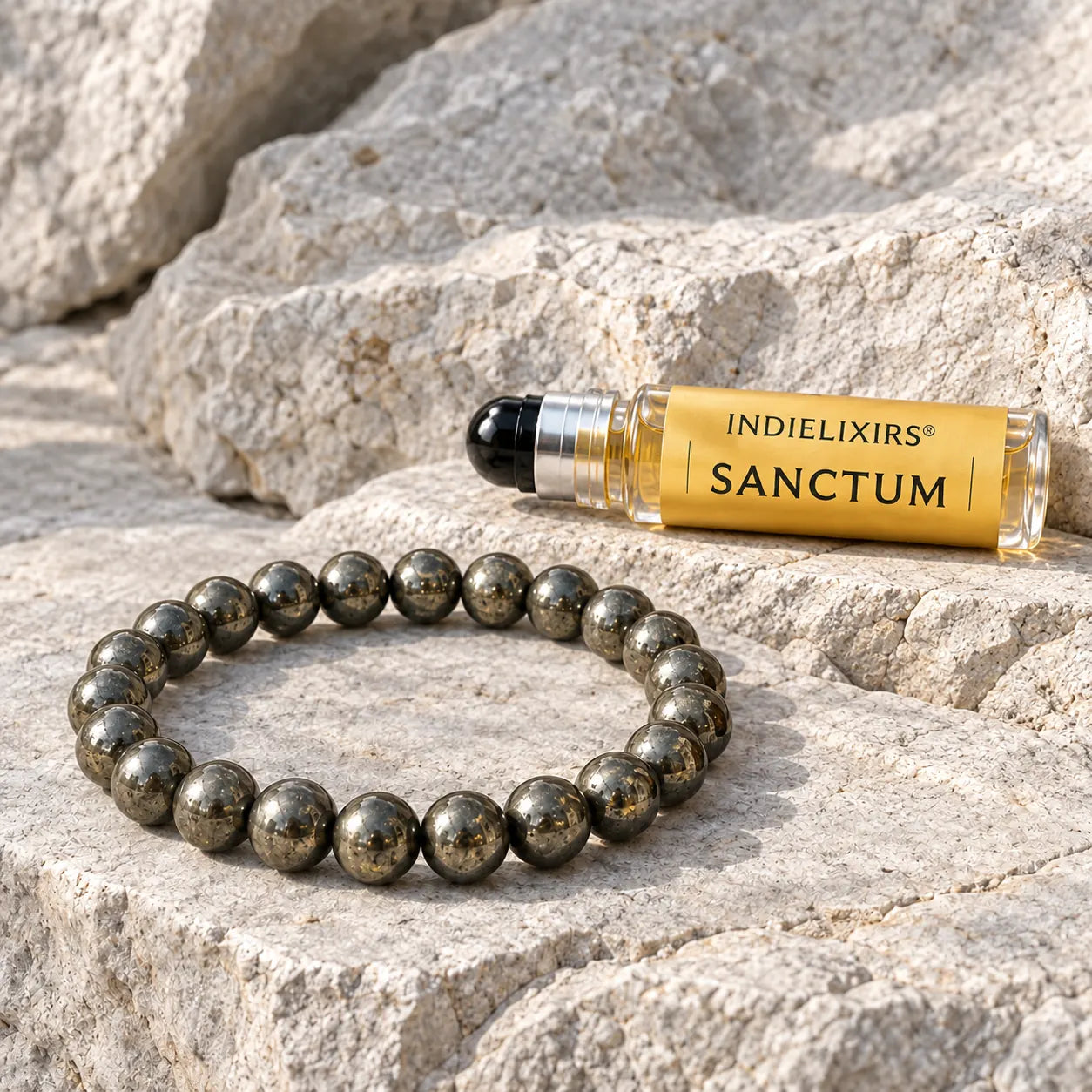 Metallic Pyrite bead bracelet beside a SANCTUM aromatic roller bottle on pale stone