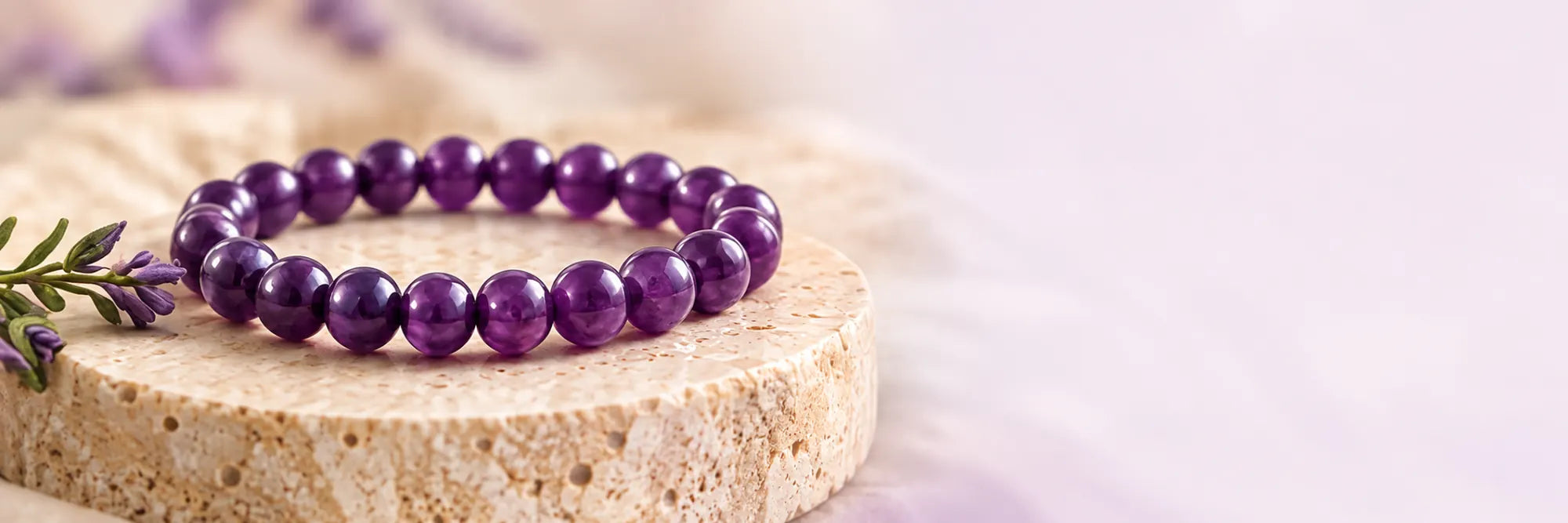 Plain polished purple Amethyst bead bracelet on pale stone, with lavender sprigs