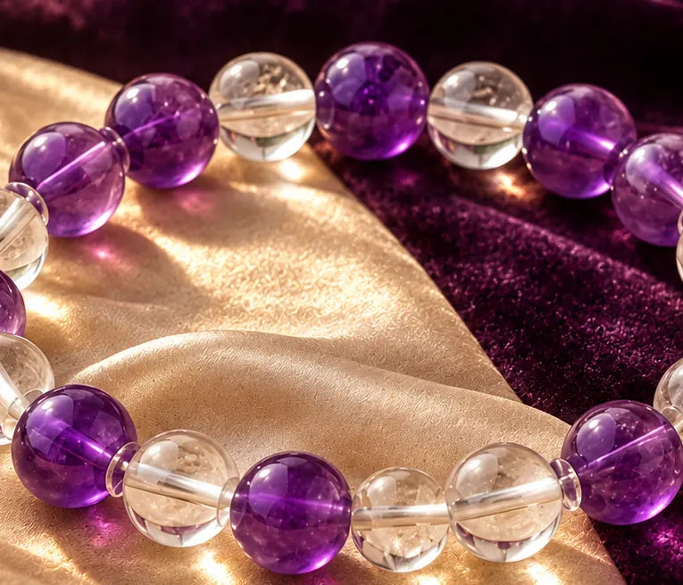 Violet and clear quartz beads resting on ivory silk